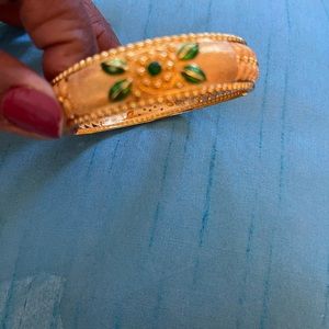 Gold tone bangles with green flower designs.